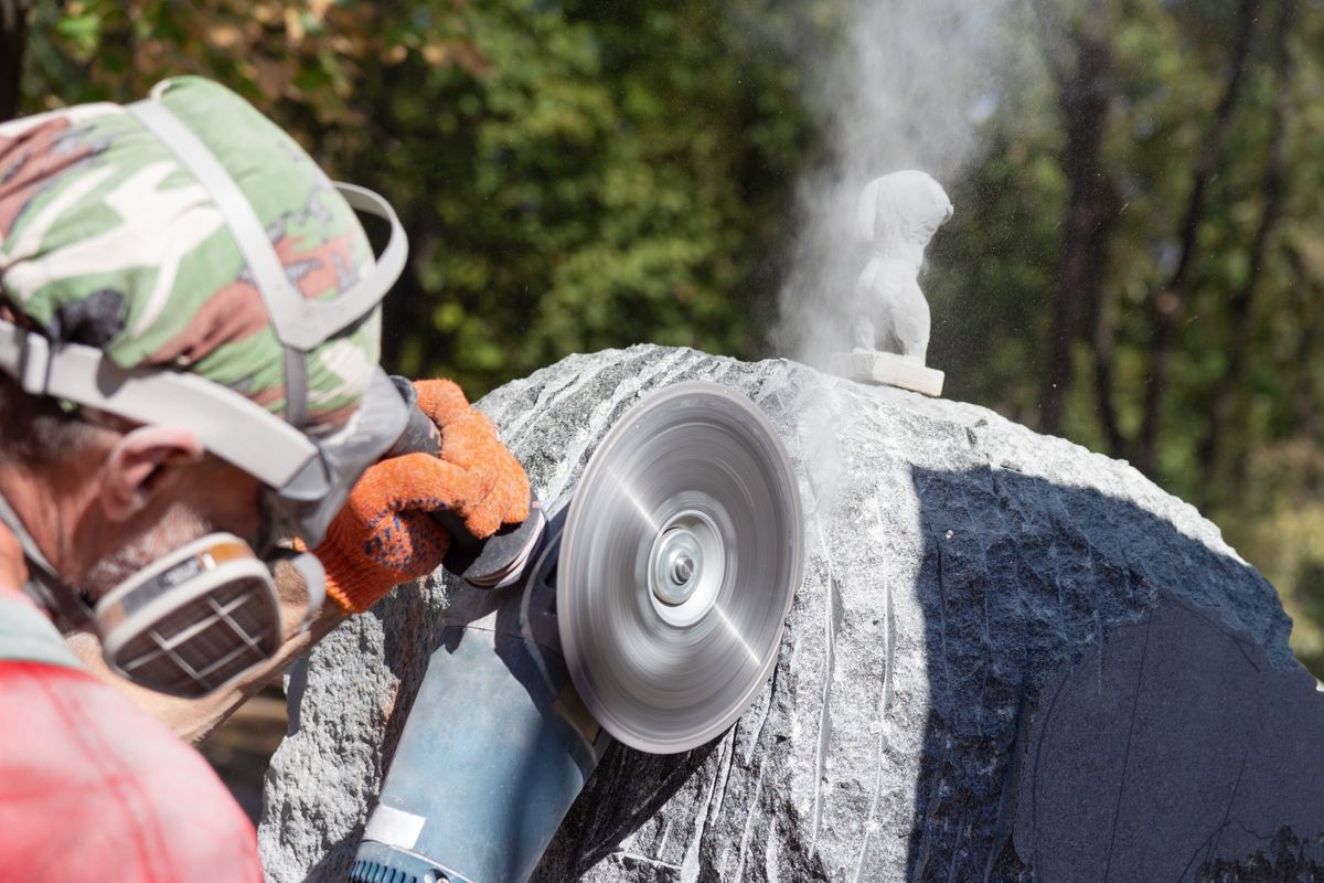 The work of the stone sculptor gabbro granite. stone cutting by grinding machine. dusty work